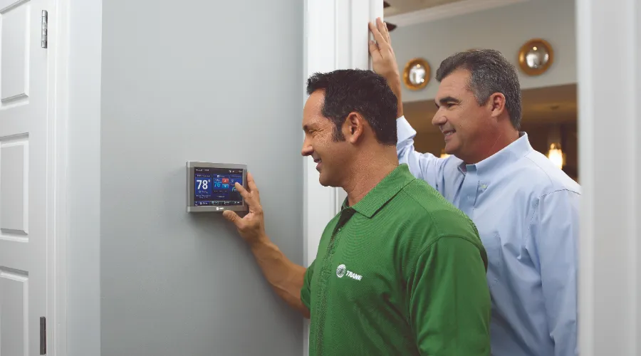 trane dealer showing homeowner how to use thermostat